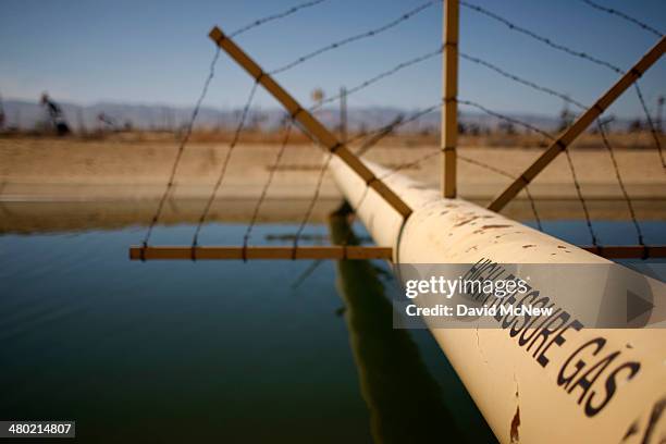 High pressure gas line crosses over a canal in an oil field over the Monterey Shale formation where gas and oil extraction using hydraulic...