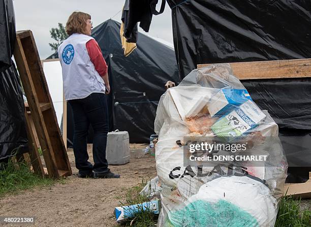 Volunteer of humanitarian NGO Medecins du Monde stands near a bin bag reading "City of Calais" on July 7 in the site dubbed "new jungle", where...