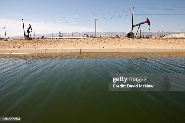 Pump jacks are seen next to a canal in an oil field over the Monterey Shale formation where gas and oil extraction using hydraulic fracturing, or...