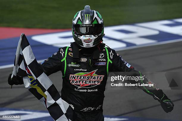 Kyle Busch, driver of the Interstate Batteries Toyota, celebrates with the checkered flag after winning the NASCAR Sprint Cup Series Auto Club 400 at...