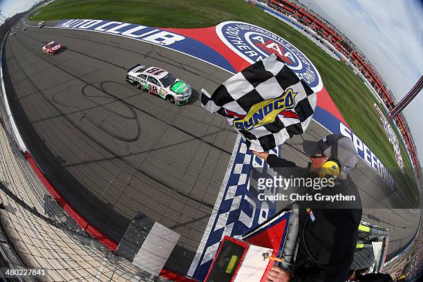 Kyle Busch, driver of the Interstate Batteries Toyota, takes the checkered flag to win the NASCAR Sprint Cup Series Auto Club 400 at Auto Club...