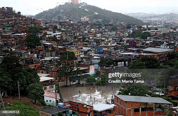 Men play soccer on a muddy field in the Complexo do Alemao pacified 'favela' community on March 23, 2014 in Rio de Janeiro, Brazil. The 'favela' was...