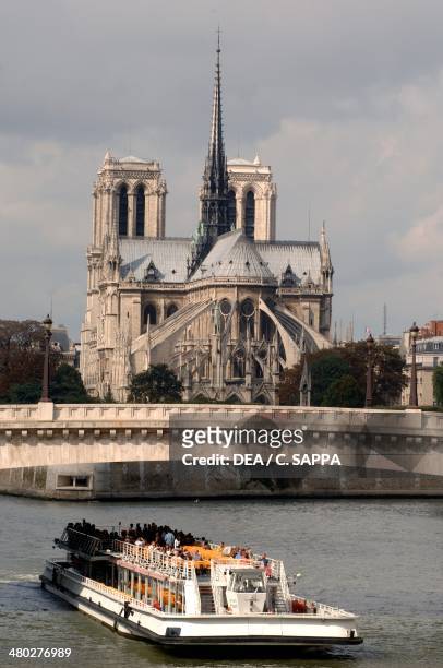 Bateau Mouche sailing on the Seine near the east facade of the Cathedral of Notre Dame de Paris , Ile de la Cite, Paris , France.