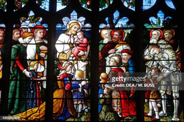 Scene with Jesus, children and donors, stained glass window in St Peter and St Paul's church , Lavenham, Suffolk, United Kingdom.