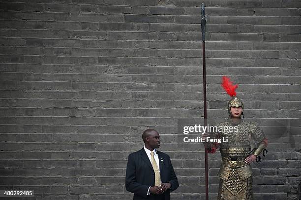 Security guard of U.S. First lady Michelle Obama stands beside a man wearing a Chinese ancient warrior costume during Obama's visit at the City Wall...