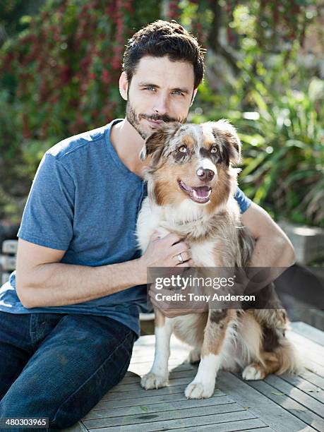 smiling men holding his dog in backyard garden - australian shepherd - fotografias e filmes do acervo