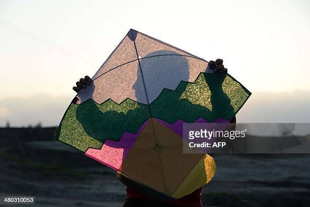 An Afghan youth holds a kite to be flown during sunset on the outskirts of Jalalabad, Nangarhar province on March 24, 2014. Some nine million Afghans...