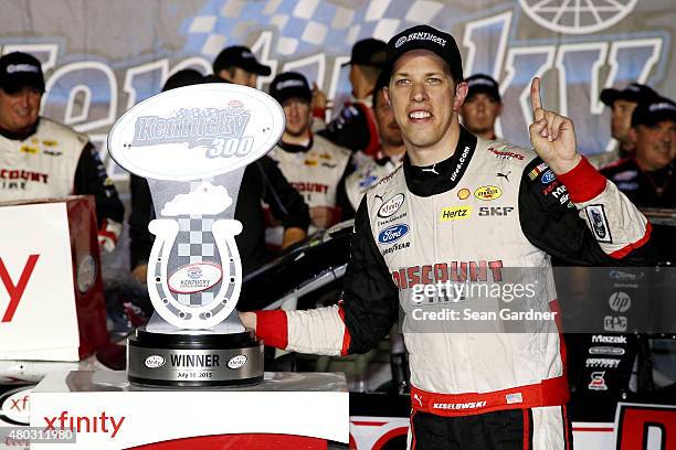 Brad Keselowski, driver of the Discount Tire Ford, poses with the winner's trophy in Victory Lane after winning the NASCAR XFINITY Series Kentucky...