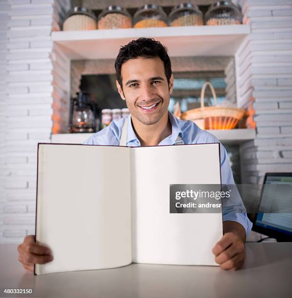 man working at a restaurant holding a menu - guest book stock pictures, royalty-free photos & images
