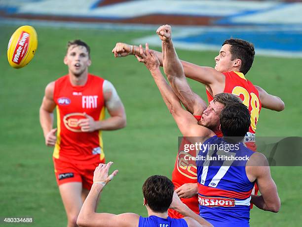 Kade Kolodjashnij of the Suns punches the ball clear ahead of Tom Boyd of the Bulldogs during the round 15 AFL match between the Western Bulldogs and...