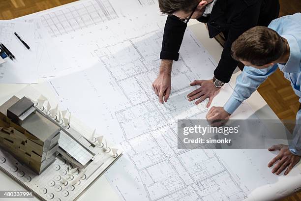 architect explaining blueprint to client - model building stockfoto's en -beelden