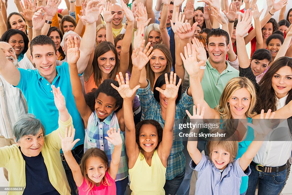 Group of happy people with arms raised looking at camera.