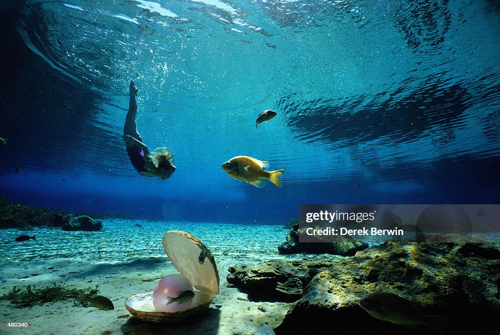 WOMAN SWIMMING UNDERWATER WITH PEARL