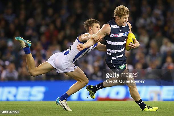 Josh Caddy of the Cats is tackled by Kayne Turner of the Kangaroos during the round 15 AFL match between the North Melbourne Kangaroos and the...