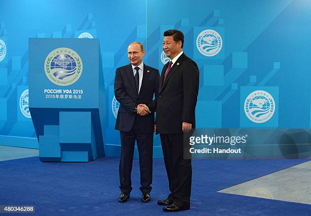 In this handout image supplied by Host Photo Agency / RIA Novosti, Russian President Vladimir Putin and President of China Xi Jinping shake hands...