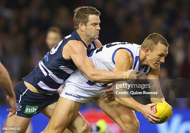 Drew Petrie of the Kangaroos is tackled by Jared Rivers of the Cats during the round 15 AFL match between the North Melbourne Kangaroos and the...