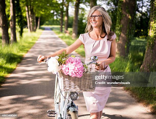 マチュアを渡る女性は彼女のクラシックな自転車公園 - bike flowers ストックフォトと画像