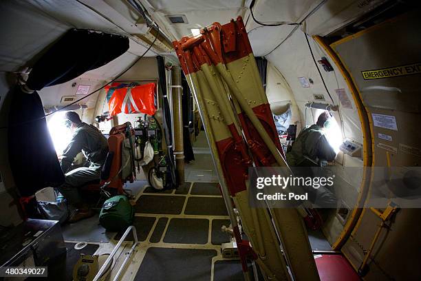 Crewman of an RAAF AP-3C Orion aircraft look out from an observation window during a search for missing Malaysia Airways Flight MH370 on March 24,...