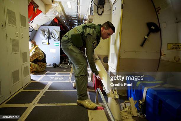 Crewman of an RAAF AP-3C Orion aircraft loads a sono buoy that will mark the location of any wreckage found during a search for missing Malaysia...