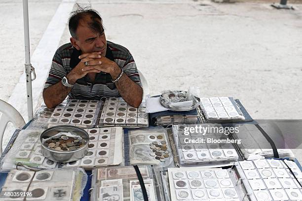 Street vendor selling old Greek drachma coins and banknotes sits at a stall at the Monastiraki flea market in Athens, Greece, on Saturday, July 11,...