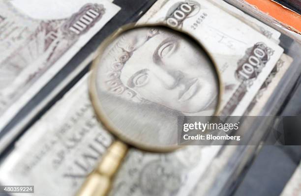 The image of the Greek god Apollo is seen through a magnifying glass on an old Greek one thousand drachma banknote as it sits on display at a street...