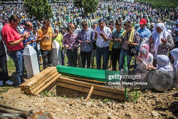 Family members and volunteers pray over one of the 136 coffins of newly-identified victims of the 1995 Srebrenica massacre next to its final grave...