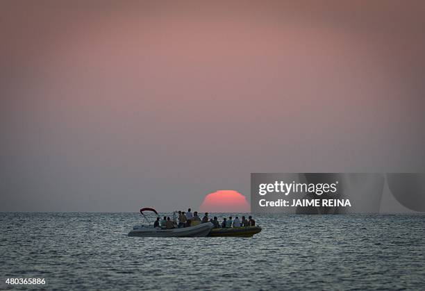 Tourists on boats enjoy the sunset off Cafe del Mar in San Antonio de Portmany, on Ibiza Island on July 10, 2015. AFP PHOTO/ JAIME REINA