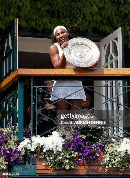 Player Serena Williams celebrates with the winner's trophy, the Venus Rosewater Dish, on the centre court balcony after her women's singles final...