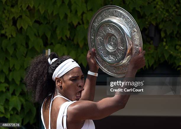 Serena Williams of the U.S.A celebrates with her winner's trophy on the clubhouse balcony in front of fans after beating Garbine Muguruza of Spain in...