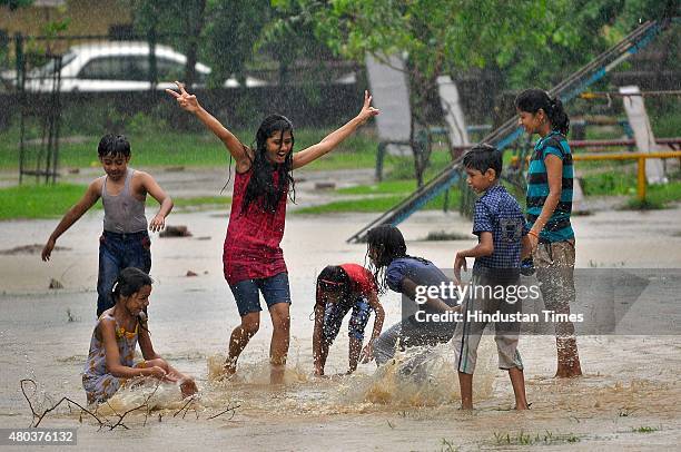 Children enjoy during heavy rain on July 11, 2015 in Noida, India. Heavy rain in Delhi/NCR brings the mercury down and causes water logging in many...