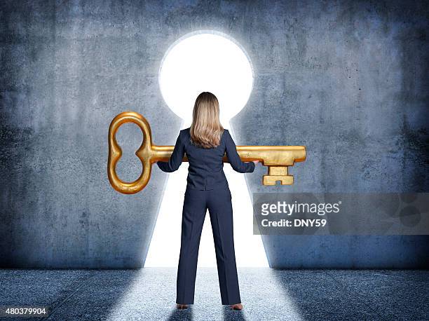 businesswoman standing in front of keyhole holding a large key - key hole bildbanksfoton och bilder