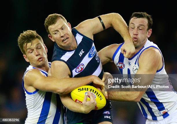 Steve Johnson of the Geelong Cats is tackled by Shaun Higgins of the North Melbourne Kangaroos and Todd Goldstein of the North Melbourne Kangaroos...