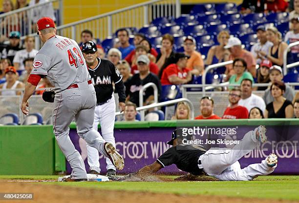 Baserunner Dee Gordon of the Miami Marlins slides safely head first into first base beating a tag by first baseman Manny Parra of the Cincinnati Reds...