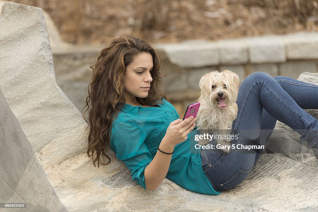 Young woman with phone and morkie dog