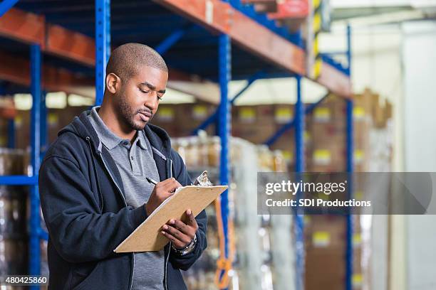 warehouse manager taking inventory in food bank pantry - clipboard stockfoto's en -beelden