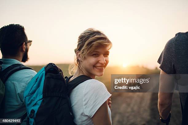 jeune femme souriante de la randonnée. - regarder par dessus son épaule photos et images de collection