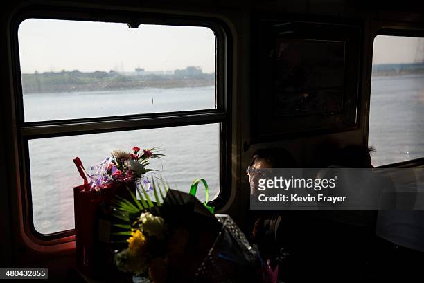 Fang Fang sits with flowers and the ashes of her father during a sea burial organized by the Funeral and Internment Administration of Shanghai on a...