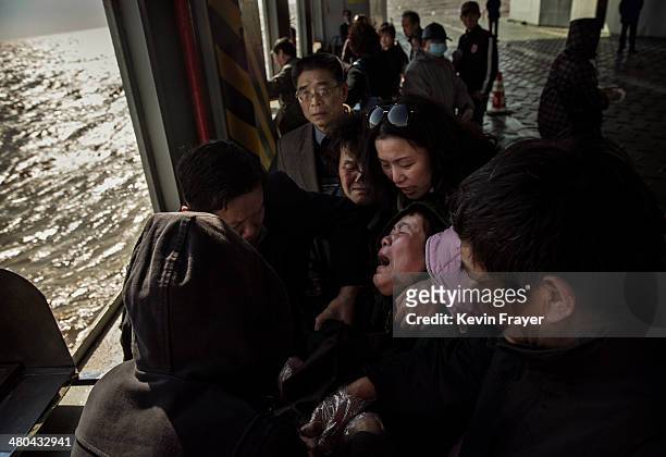 Chinese woman weeps as she reacts after placing the ashes of a relative in a metal chute during a sea burial organized by the Funeral and Internment...