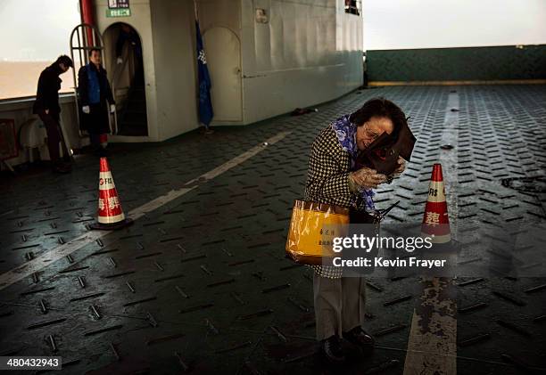 Lin Hui Zhen, 76 years, weeps as she clutches the small bag carrying the ashes of her late husband Fu Yao Ming, 80 years, before placing them in a...
