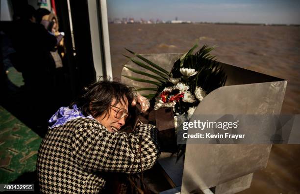 Lin Hui Zhen, 76 years, weeps as she clutches the small bag carrying the ashes of her late husband Fu Yao Ming, 80 years, before placing them in a...