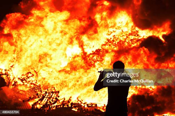 Iain McFarland, an Orange bandsman, plays his flute during the 11th night bonfire at the New Mossley housing estate on July 12, 2015 in Belfast,...