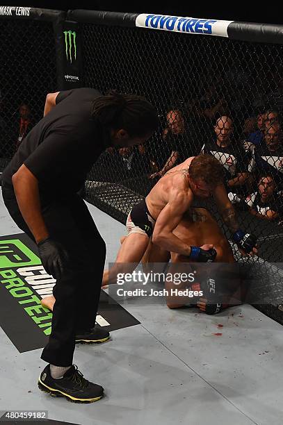 Conor McGregor punches Chad Mendes as the referee looks on in their UFC interim featherweight title fight during the UFC 189 event inside MGM Grand...