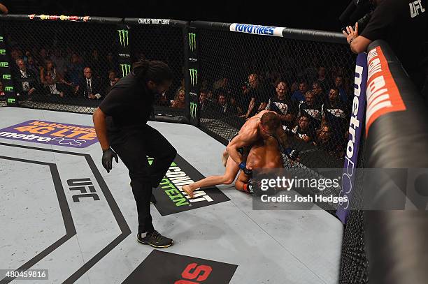 Conor McGregor punches Chad Mendes as the referee looks on in their UFC interim featherweight title fight during the UFC 189 event inside MGM Grand...