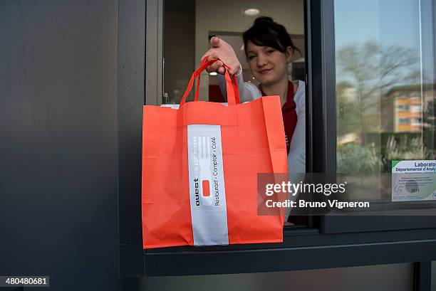 Memeber of staff passes a food order to a customer in a car at the drive-thru of Paul Bocuse's 'Ouest Express' fast food restaurant on March 13, 2014...