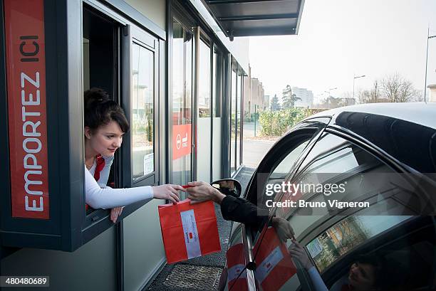 Customer in a car receives their order at the drive-thru of Paul Bocuse's 'Ouest Express' fast food restaurant on March 13, 2014 in...