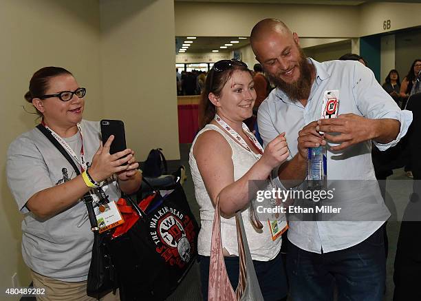 Actor Travis Fimmel takes a photo with a guest after a panel for the History series "Vikings" during Comic-Con International 2015 at the San Diego...