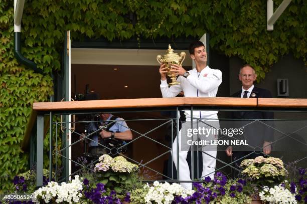 Serbia's Novak Djokovic holds the winner's trophy on the centre court balcony after his men's singles final victory over Switzerland's Roger Federer...