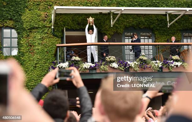 Serbia's Novak Djokovic holds the winner's trophy on the centre court balcony after his men's singles final victory over Switzerland's Roger Federer...