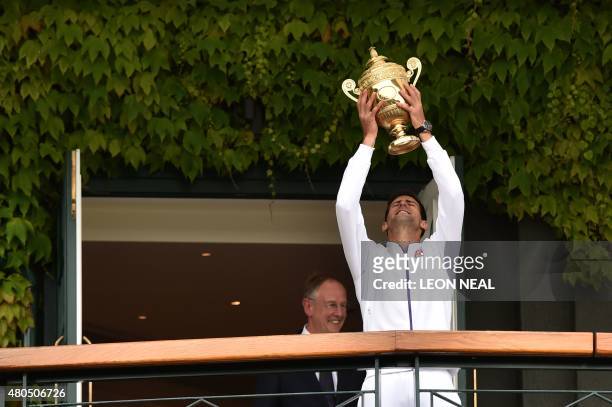 Serbia's Novak Djokovic holds the winner's trophy on the centre court balcony after his men's singles final victory over Switzerland's Roger Federer...