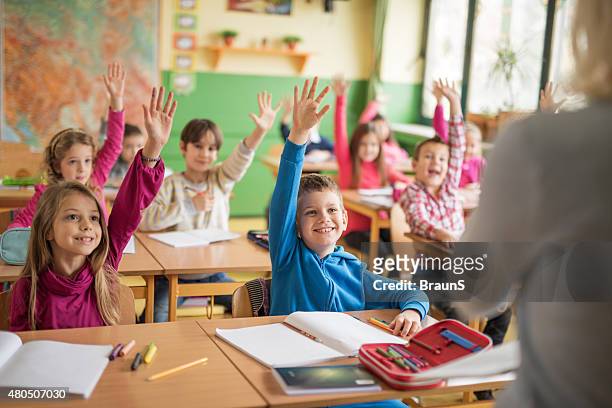 school children raising their hands ready to answer the question. - elementary school building stock pictures, royalty-free photos & images